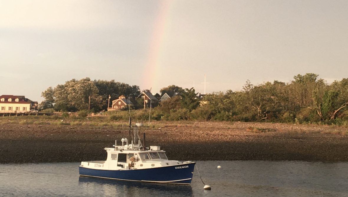 Boat with a rainbow behind and above it.